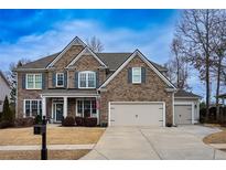 Brick two-story house with a three-car garage and manicured lawn at 5008 Bayborough Dr, Hoschton, GA 30548