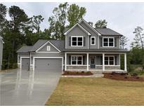 Charming two-story home with a covered front porch, gray siding, and a spacious three-car garage at 1064 Cottonwood Ln, Loganville, GA 30052