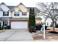 Two-story townhome with yellow siding, brick accents, and a white garage door at 2374 Suwanee Pointe Dr, Lawrenceville, GA 30043