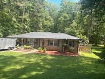 Charming single-story home with a well-manicured lawn and a lush, green treeline in the background at 6625 Starling Sw Pl, Mableton, GA 30126