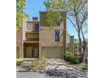 Tan two-story townhome with attached garage and landscaping at 1107 Riverbend Club Se Dr, Atlanta, GA 30339