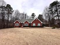 Brick house with large yard, mature trees and a paved driveway at 3648 Clark Hill Way, Buford, GA 30519