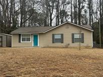 Charming single-story home with neutral siding, a well-maintained lawn, and a vibrant blue front door at 22 Cardinal Ln, Jonesboro, GA 30238