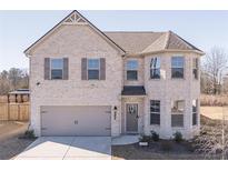 Two-story house with light brick exterior, gray garage door, and landscaping at 2797 Malton Way, Loganville, GA 30052