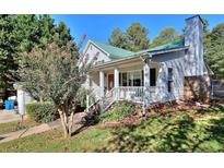Charming home featuring a covered front porch, green roof, and lush landscaping at 381 Mount Moriah Rd, Auburn, GA 30011