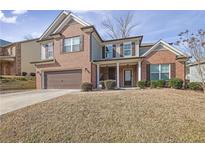 Two story home featuring brick and siding, an attached two car garage, and a covered front porch at 1202 Ida Woods Ln, Lawrenceville, GA 30045