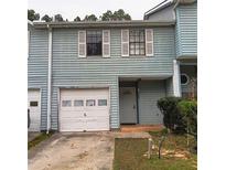 Light blue two-story townhouse with white garage door and shutters at 1604 Pine Tree Trl, Atlanta, GA 30349