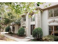 Two-story house with light beige siding, arched entryway, and landscaping at 255 Grogans Lake Pt, Atlanta, GA 30350