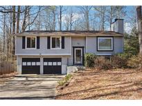 Split-level home featuring two-car garage, neutral siding, and a chimney, blending suburban charm with functional design at 190 Hembree Forest Cir, Roswell, GA 30076