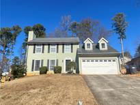 Two-story house with light green siding, attached garage, and manicured lawn at 1129 Realm Ln, Lawrenceville, GA 30044