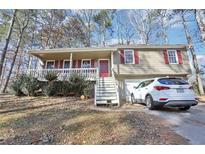 Tan house with red shutters, white porch, and a car parked in the driveway at 65 Bridge Dr, Douglasville, GA 30134