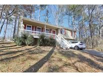 Charming home with a welcoming front porch and well-maintained yard and a white car parked in the drive at 65 Bridge Dr, Douglasville, GA 30134