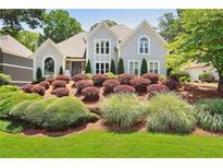 Stunning two-story home featuring lush landscaping with vibrant bushes and healthy green grass at 945 Ashebrooke Ne Trce, Marietta, GA 30068
