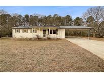 White ranch house with carport and mature trees at 24 Valerie Ln, Powder Springs, GA 30127