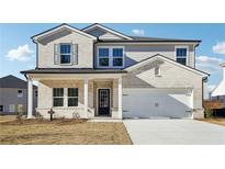 Two-story house with light brick and gray siding, a white two-car garage, and a front porch at 1569 High Falls Ln, Grayson, GA 30017