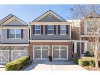 Two-story townhome featuring a brick facade, gray siding, shutters, and a two-car garage at 1584 Richmond Se Dr, Mableton, GA 30126
