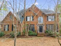 Charming brick two-story home with mature landscaping, arched window, and dark shutters at 785 Charleston Dr, Roswell, GA 30075