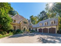 Stone and shingle exterior of a luxurious home with a large driveway and 3-car garage at 2167 W Wesley Nw Rd, Atlanta, GA 30327