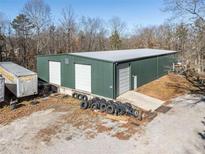 Large green metal building with three garage doors and a concrete pad at 200 Heath Rd, Carrollton, GA 30116