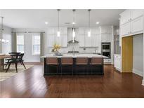 Modern kitchen with white cabinets, stainless steel appliances, and large island with seating at 6540 Namon Creek Trl, Cumming, GA 30028