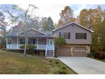 Two-story house with brown siding, white porch, and attached two-car garage at 1129 Gate Post Ln, Lawrenceville, GA 30044