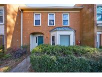 Brick townhouse exterior featuring a charming green door and well-manicured landscaping at 4154 Oakwood Way, Duluth, GA 30096