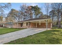 Charming single-story brick home featuring a long driveway and a covered parking area with decorative iron supports at 2643 Oswood Dr, Tucker, GA 30084