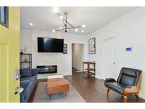 Bright living room features a modern fireplace with stone surround, hardwood floors, and stylish light fixture at 1018 Westmont Sw Rd, Atlanta, GA 30311