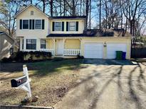 Two-story yellow house with a white garage and landscaped yard at 5615 Pennybrook Ct, Stone Mountain, GA 30087