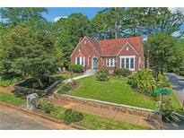 Charming brick Tudor home featuring a manicured lawn and red tile roof at 1290 Pasadena Ne Ave, Atlanta, GA 30306
