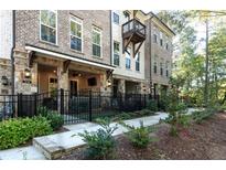 Charming townhome exterior features brick and stone, a landscaped yard, and a quaint black iron fence at 418 Townly, Alpharetta, GA 30009