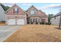 Brick two-story house with a three-car garage and landscaped yard at 1724 Stone Meadow Rd, Lithonia, GA 30058