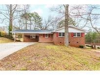 Charming brick home featuring a covered carport, red shutters and mature trees at 6076 Shortleaf Dr, Forest Park, GA 30297