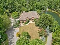 A beautiful aerial view of the brick house with a pond and circular driveway surrounded by a lush green landscape at 3505 Watson Rd, Cumming, GA 30028