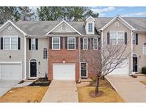 Three-unit townhome complex with brick and siding exteriors, featuring attached garages and landscaping at 438 Lantern Wood Dr, Scottdale, GA 30079