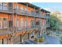 Brick townhome with multiple levels of balconies and attached garage at 235 Founders Mill Ct, Roswell, GA 30075