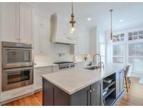 Modern kitchen featuring a large island, stainless steel appliances, and stylish pendant lighting at 235 Founders Mill Ct, Roswell, GA 30075