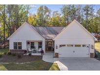 White farmhouse exterior with stone accents, two-car garage, and landscaped yard at 728 Harmony Rd, Temple, GA 30179