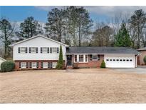 Ranch style home with brick and white siding, attached garage, and spacious yard at 1833 Queens Way, Chamblee, GA 30341