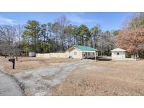 Ranch home with green roof, carport, and detached shed on a wooded lot at 4785 Old Douglasville Rd, Lithia Springs, GA 30122