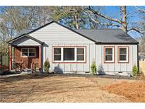 Charming bungalow with gray siding, black roof, and well-manicured front yard ready for a new homeowner at 1956 Gober Se Ave, Smyrna, GA 30080