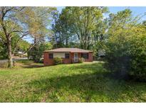 Cozy brick home with a small front porch and a spacious front yard surrounded by mature trees at 3777 Crosby Nw Dr, Atlanta, GA 30331