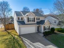 Two-story house with beige vinyl siding, a white garage door, and landscaping at 104 Holly Mill Village Dr, Canton, GA 30114