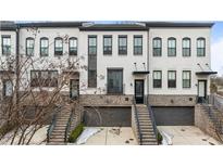 White brick townhome with gray accents, two-car garage, and steps leading to the entrance at 1388 La France Ne St # 10, Atlanta, GA 30307