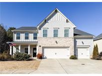 Two-story home with gray siding, brick accents, and a three-car garage at 3985 Starwood Dr, Cumming, GA 30028