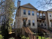 Inviting townhouse features a brick facade, multi-pane windows, and a charming entrance with elevated front yard at 124 Everley Walk, Alpharetta, GA 30009