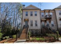 Brick front exterior of a charming townhome with a fenced yard and landscaping at 124 Everley Walk, Alpharetta, GA 30009