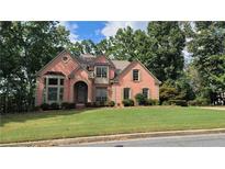 Brick house with a large front yard and mature trees at 5915 Masters Club Dr, Suwanee, GA 30024