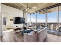 Bright living room featuring a neutral sofa, flat-screen TV, concrete ceilings, and stunning city views from floor-to-ceiling windows at 860 Peachtree Ne St # 2618, Atlanta, GA 30308