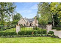 Brick house with gated entrance, manicured lawn, and mature trees at 4706 Powers Ferry Rd, Atlanta, GA 30327